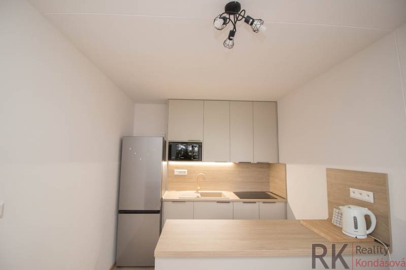 A kitchen in a 3-room apartment with a countertop, refrigerator, and stovetop.