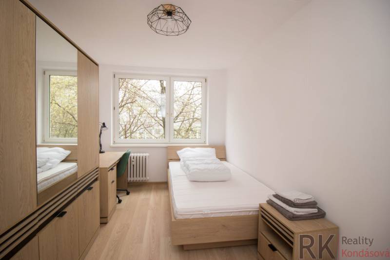 A room in a 3-room apartment with a bed, a table, and a floor with a wooden decor.