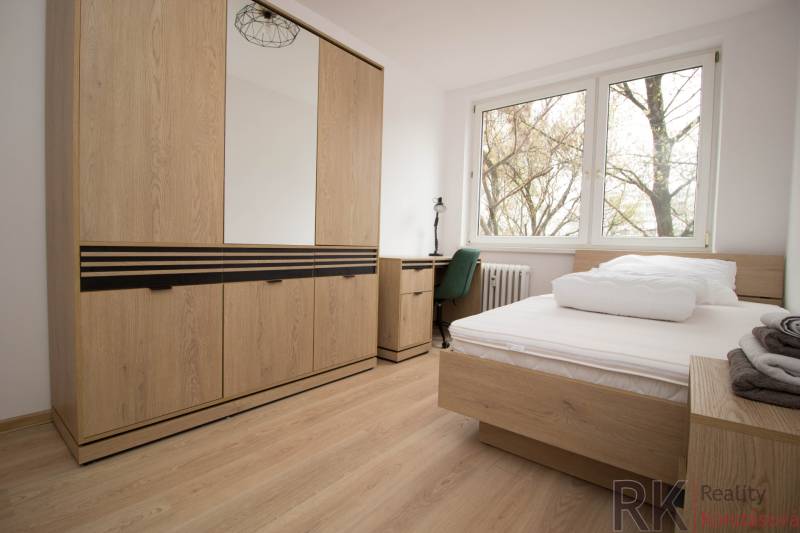 Bedroom in a 3-room apartment with a bed, wardrobe, and floor with wooden decor.