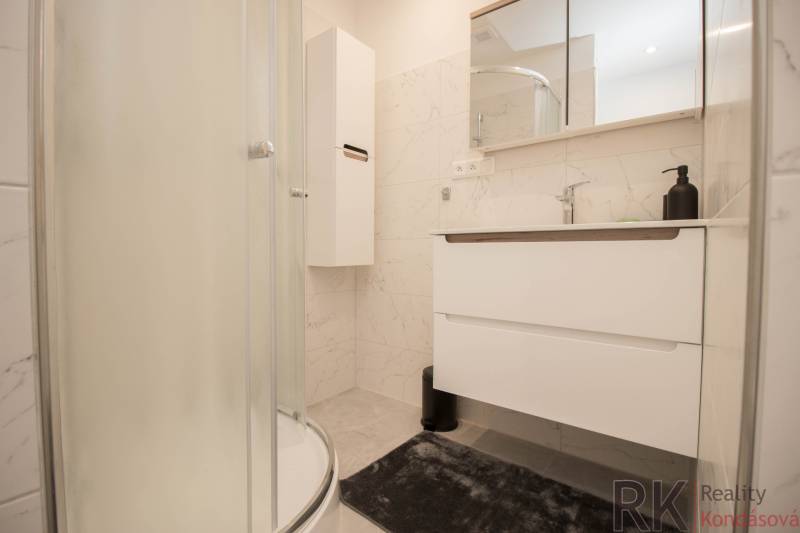 A bathroom in a 3-room apartment with a modern shower and white furniture.