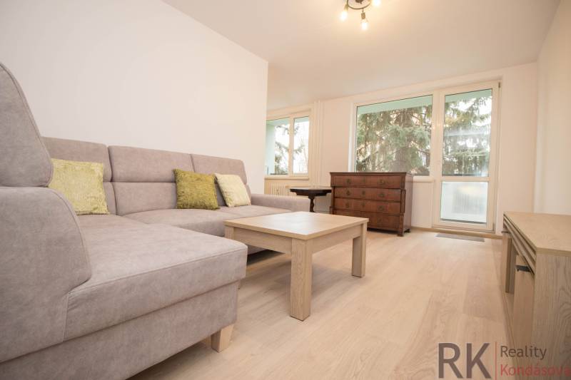 Living room with a sofa, table, and wooden decor flooring in a 3-room apartment.