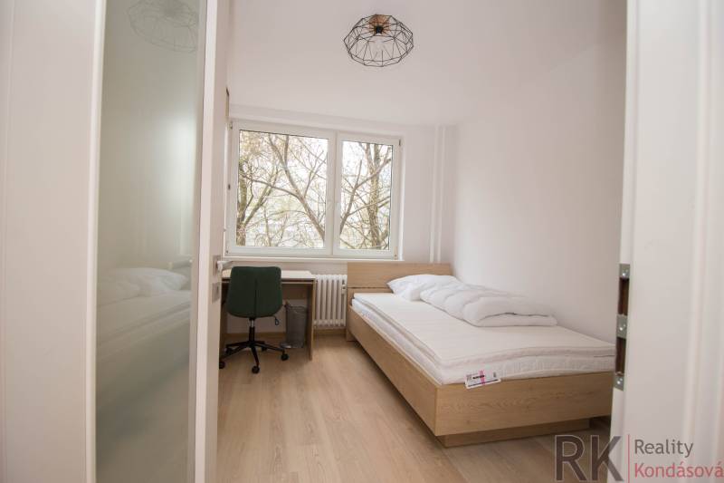 A single bedroom with a bed, a desk, and a wooden floor decor in a three-room apartment.