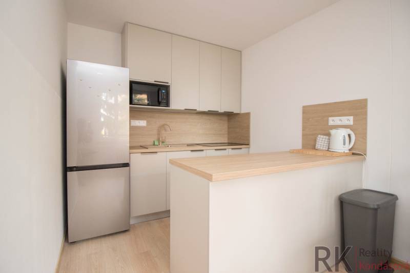 A kitchen in a 3-room apartment with a wooden decor floor and modern appliances.