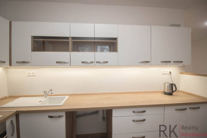 A kitchen unit in a 2-room apartment with a wooden decor countertop.