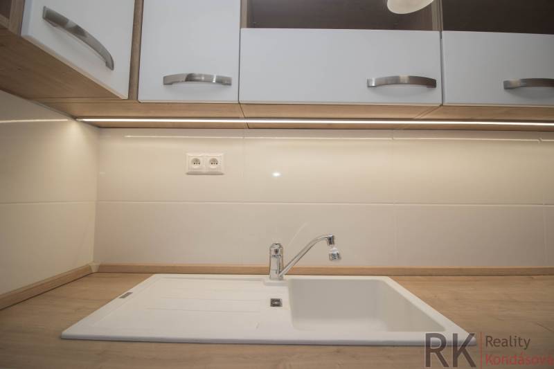 A kitchen countertop with a wood decor and a white sink in a 2-room apartment.