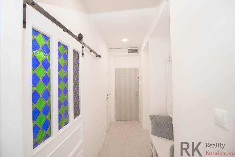 A hallway with stained glass doors, coat racks, and wooden decor in a 2-room apartment.