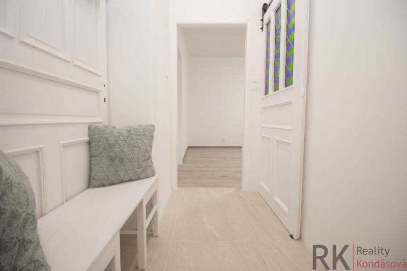 A bright hallway with white furniture and decorative cushions in a 2-room apartment.