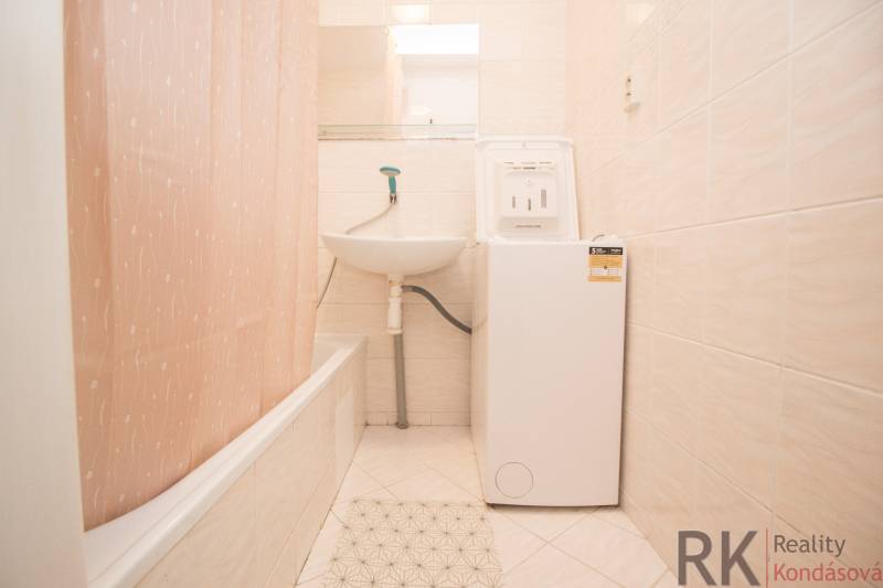 A bathroom with a shower curtain, a sink, and a washing machine in a 4-room apartment.