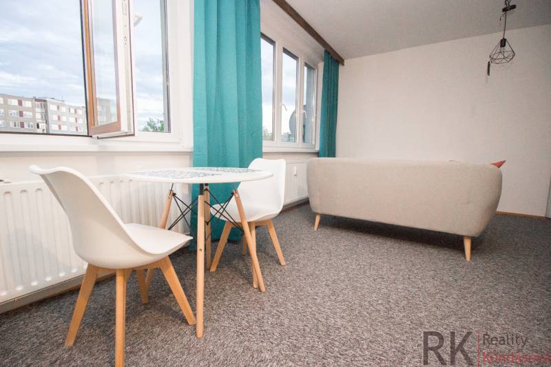 Living room with a table and chairs in a 4-room apartment, bright curtains, light carpet.