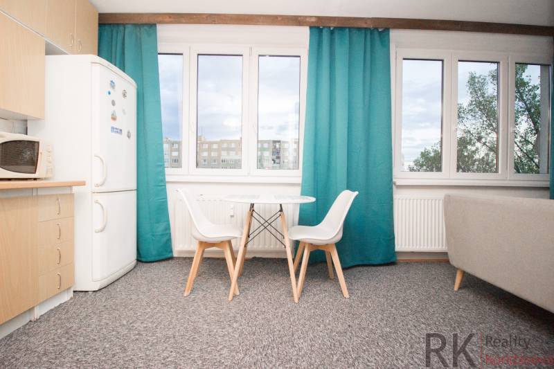 A kitchen with a table and chairs in a 4-room apartment, a wardrobe, and windows with turquoise curtains.