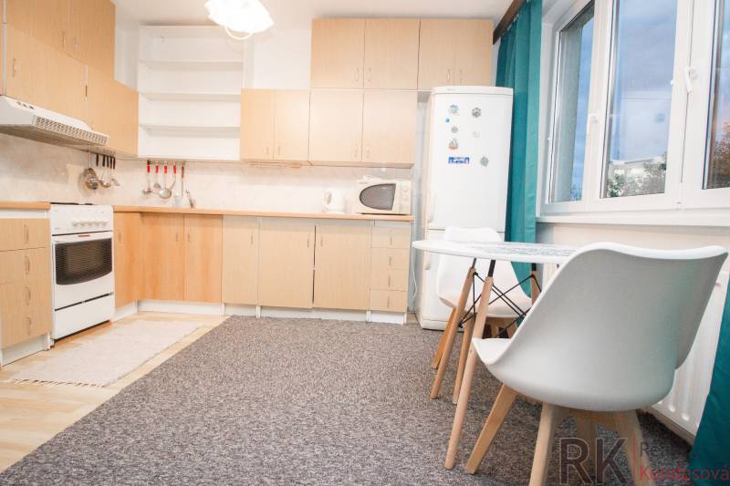 A kitchen with white furniture and a dining table in a 4-room apartment.