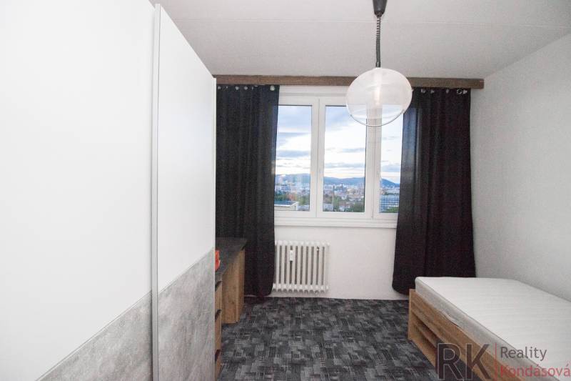 A room in a 4-room apartment with a bed, dark curtains, and a view from the window.