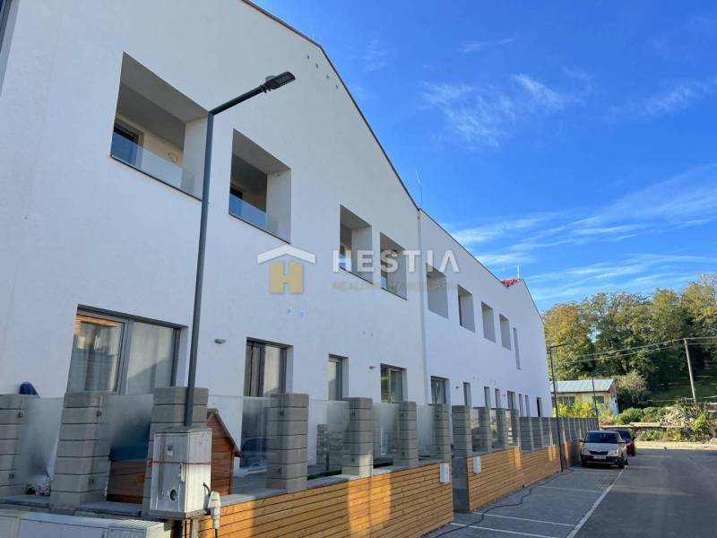 Exterior of an apartment building with parking, surrounding nature, ideal for purchasing a 2-bedroom apartment.