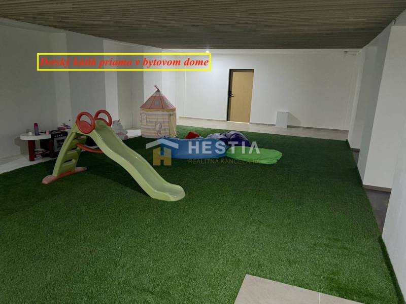 A children's corner with artificial grass, a slide, and a tent in a 2-room apartment.