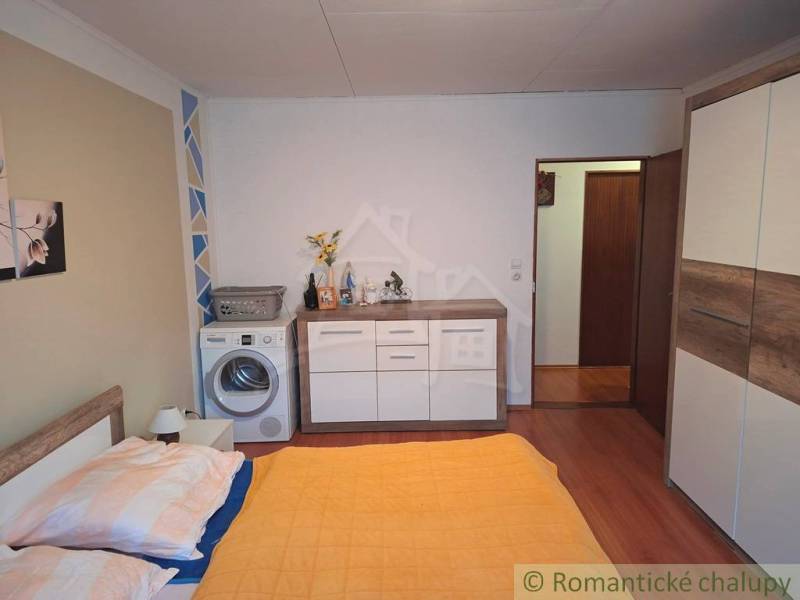 Bedroom in a family house with a washing machine, wardrobe, and wooden floor decor.