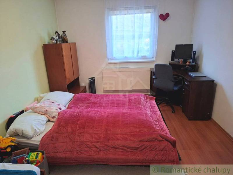 A bedroom in a family house with a bed, a desk, and a wooden decor floor.
