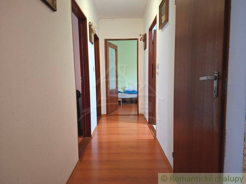 A hallway with a wooden decor floor in a family house, entrance to the rooms.