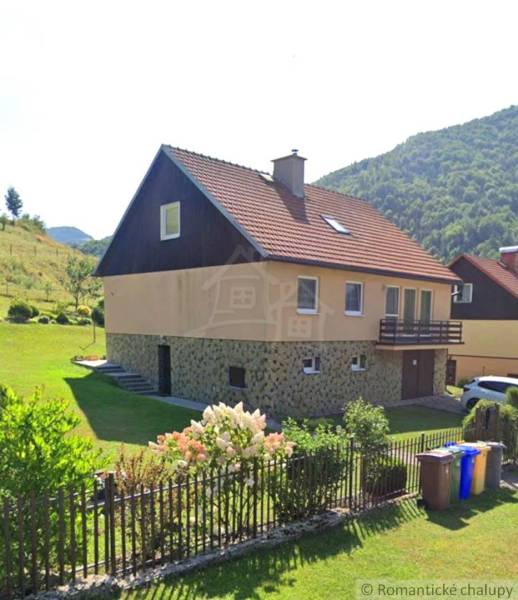 A family house in Liptovské Revúce with a red roof, a garden, and a flower fence.