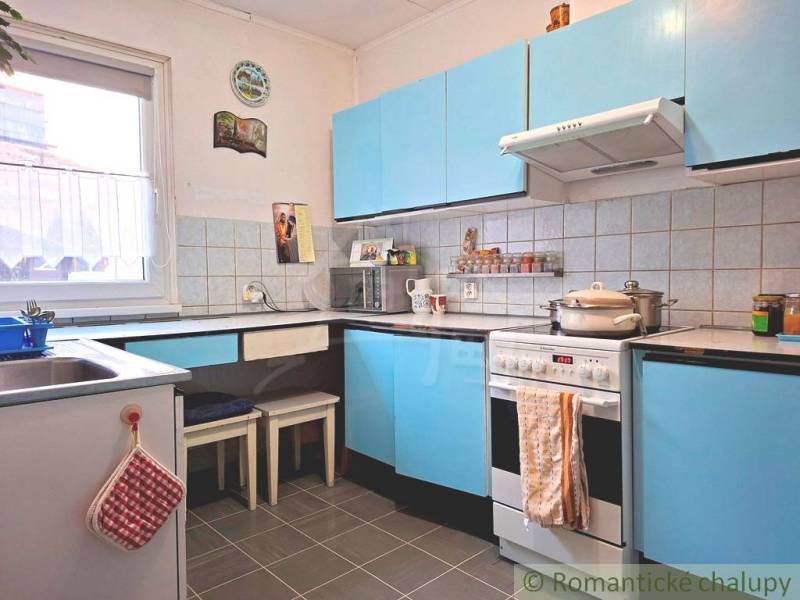 A kitchen in a family house with blue cabinets and a tiled wall.