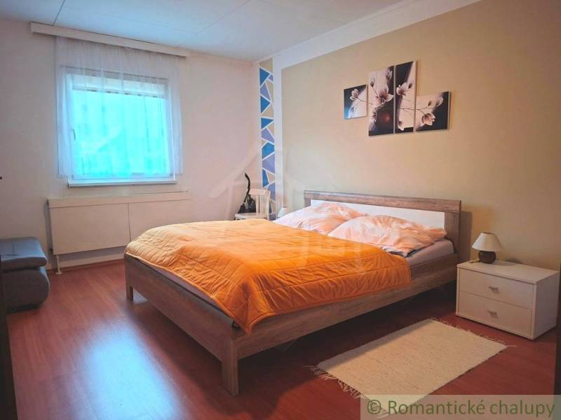 A bedroom in a family house with a bed, decoration, and a floor with a wooden design.