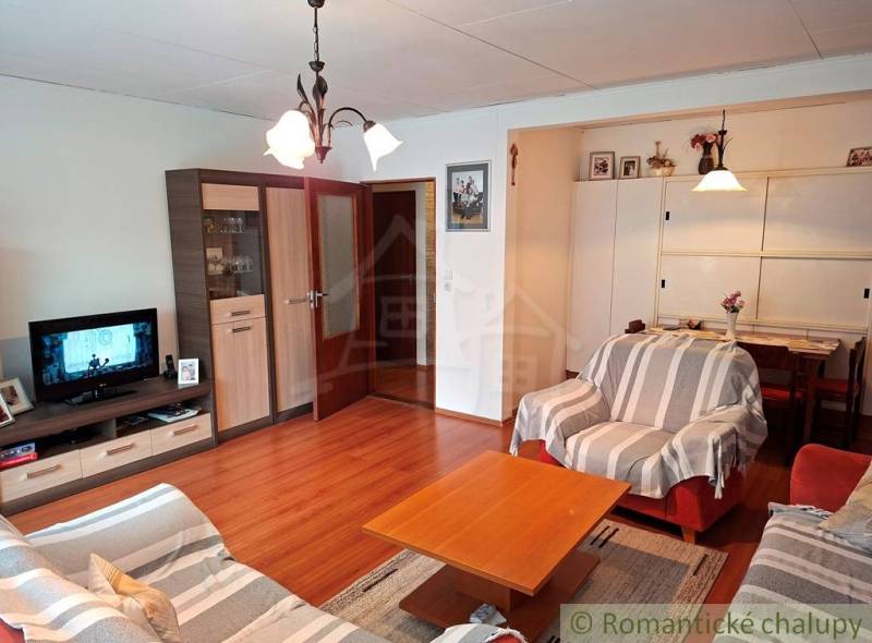 Living room in a family house with comfortable sofas and a wooden-patterned floor.