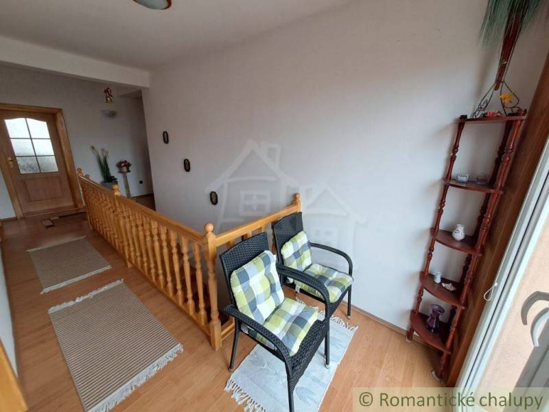 Interior of a family house with a staircase, chairs, and a floor with a wooden decor.