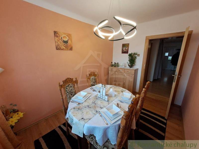 A stylish dining room of a family house, highlighted by a light and neatly arranged tablecloth, as well as a distinctive chandelier.