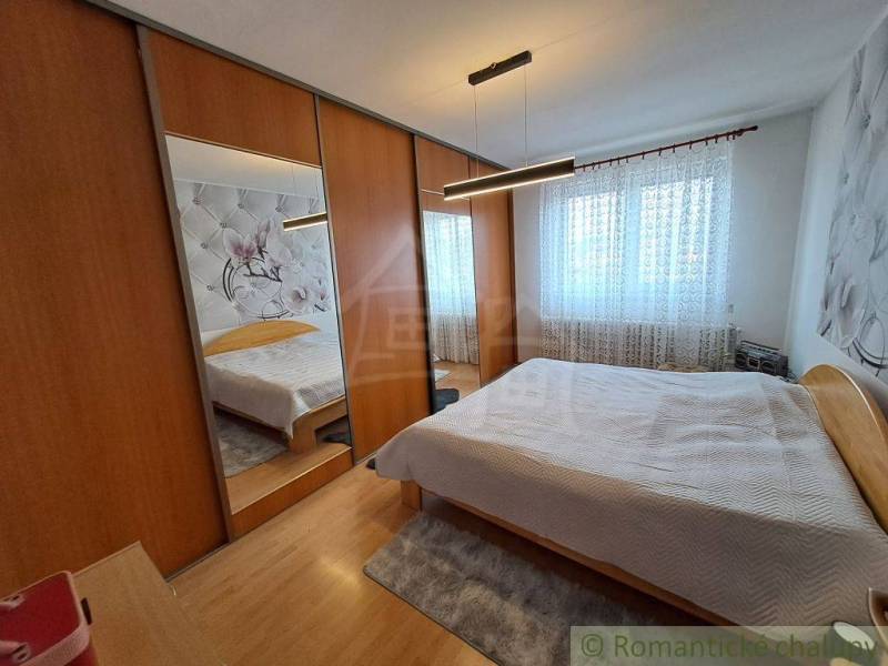 A bedroom in a family house with mirrored wardrobes and a wooden decor floor.
