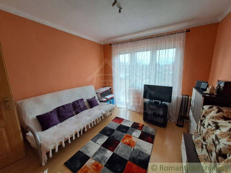 Living room in a family house with wood-patterned flooring and orange walls.