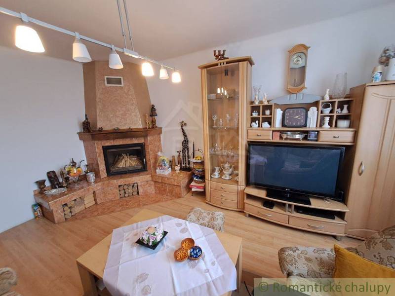 Living room in a family house with a fireplace, wooden floor decor, and a display cabinet.