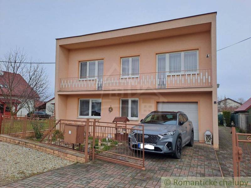A family house in Veľké Ripňany with a balcony and a car on the driveway.