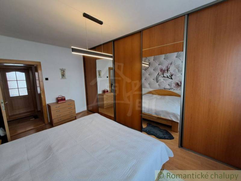 A bedroom in a family house with a wooden decor floor and a large wardrobe.
