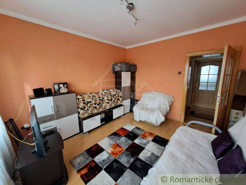 Living room in a family house with furniture, television, and wooden decor flooring.