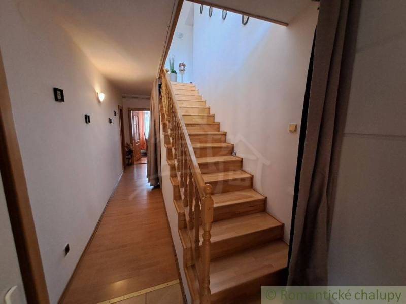 A hallway of a family house with wooden stairs and a floor with a wooden decor.
