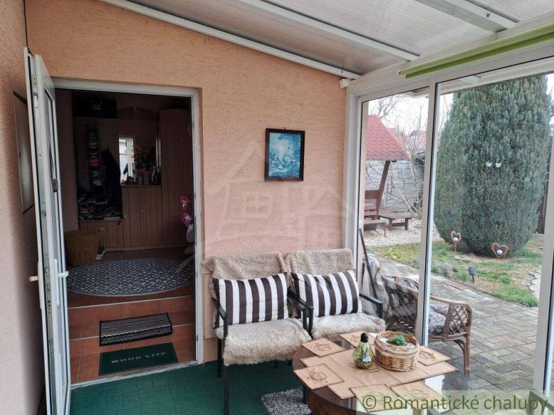 A winter garden in a family house with comfortable seating and a view of the garden.