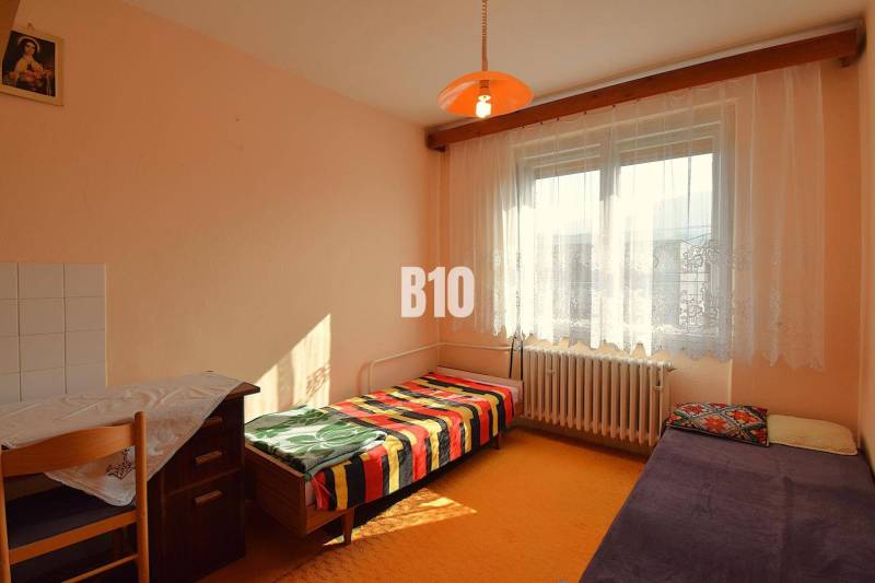 A room in a family house with simple furniture, a bed, and an orange lantern.