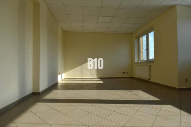 Bright empty room and office with a window and radiator, beige walls.