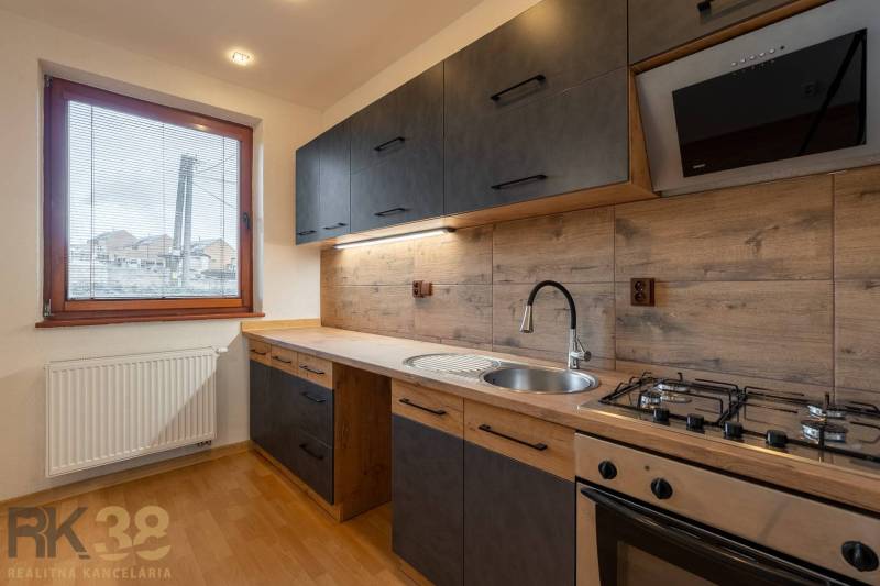 A kitchen in a 5 or more room apartment with an elegant kitchen unit and a wooden decor floor.