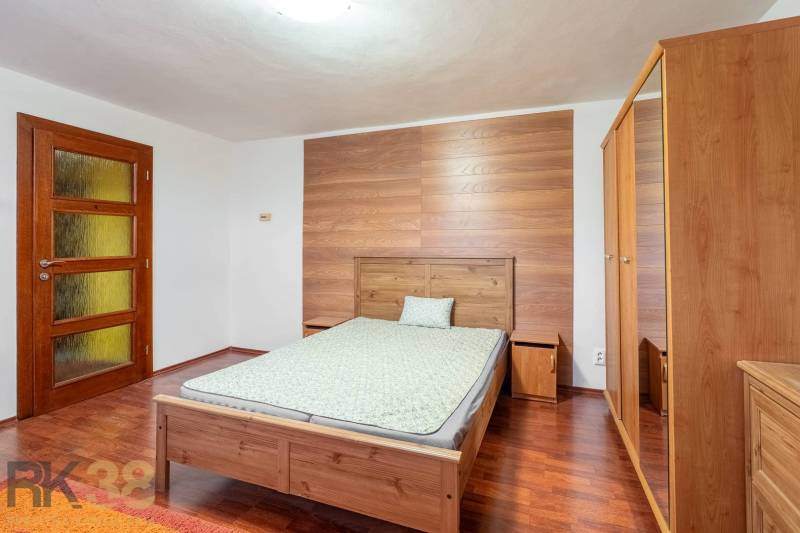 A bedroom in a 5 or more room apartment with a wood-patterned floor, wooden furniture.
