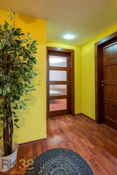 A hallway in a 5 or more-room apartment with a wooden decor floor and yellow walls.