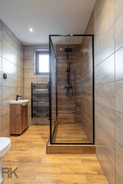 A bathroom in a 5 or more room apartment with a wooden decor floor and a shower corner.