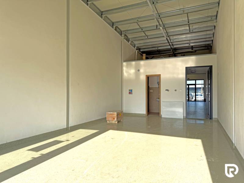 Spacious commercial premises with high ceilings and concrete flooring.
