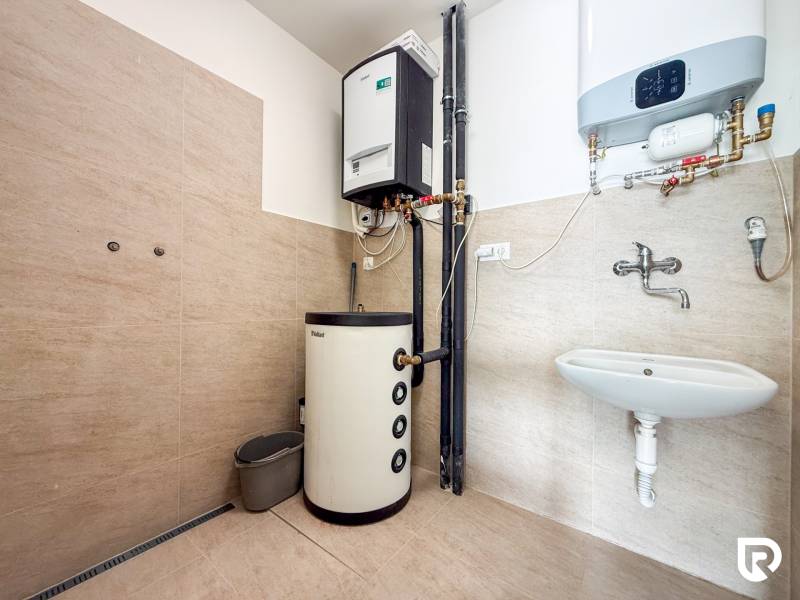 Interior of commercial premises with a heating system, sink, and floor with wood decor.