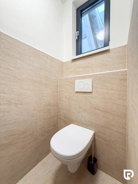 A restroom with natural tiling in commercial premises, simple design and a window.