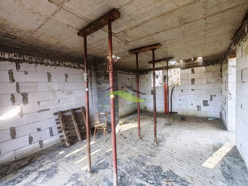 The interior of the cottage under construction with temporary supports, exposed bricks, and building material.