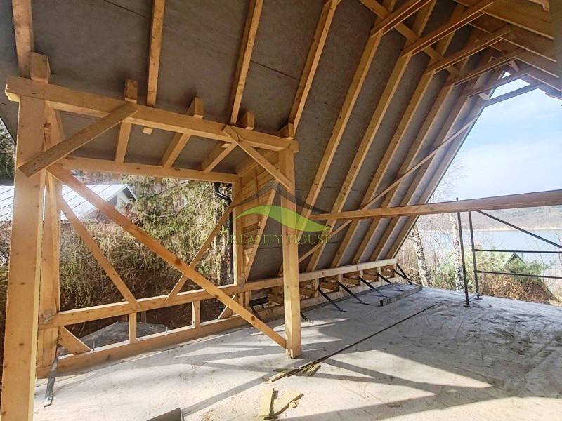 An unfinished cabin with a wooden structure at Zajačia debra in Holčíkovce, overlooking the river.