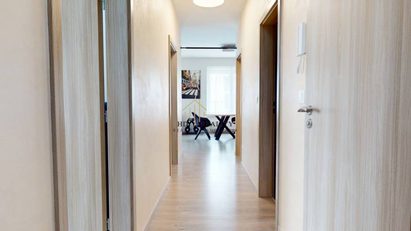 A corridor with a wooden decor floor leading to a 3-room apartment.