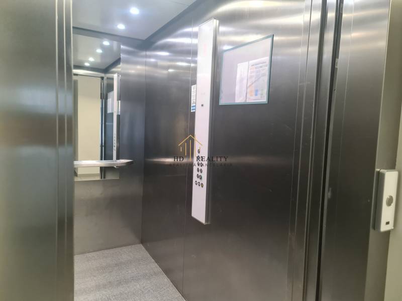 A metal elevator cabin with lighting and a mirror in a 3-room apartment.