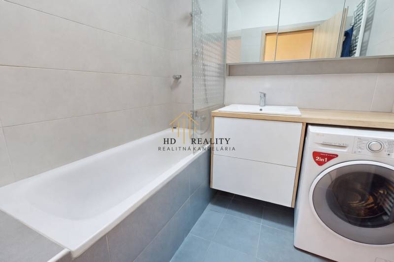 Bathroom with a bathtub, sink, mirror, and washing machine in a 3-room apartment.
