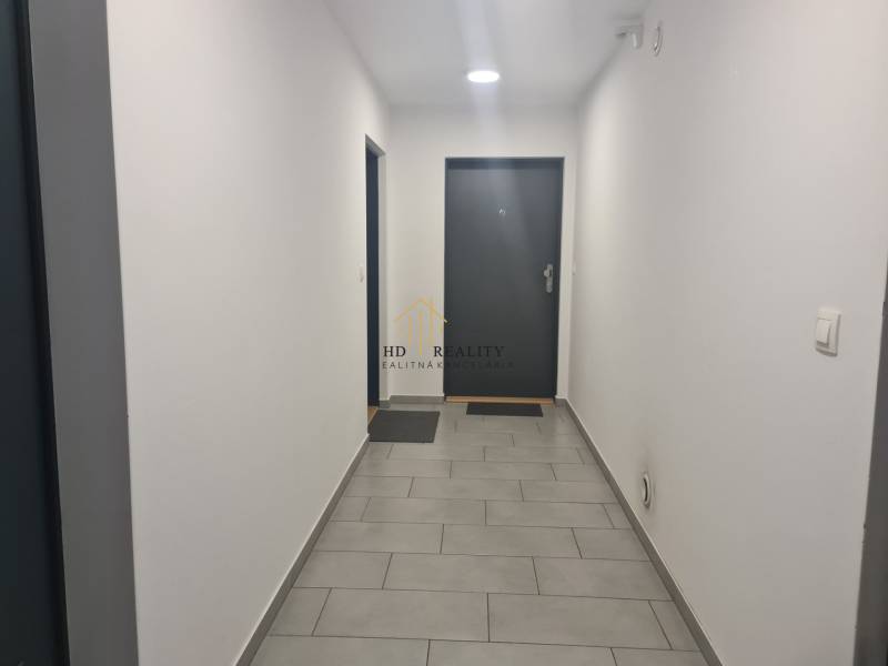 The interior of a hallway with white walls and gray tiles in a 3-room apartment.